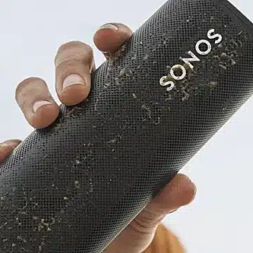 Το φορητό ηχείο Sonos Roam λασπωμένο, το κρατάει ένα γυναικείο χέρι